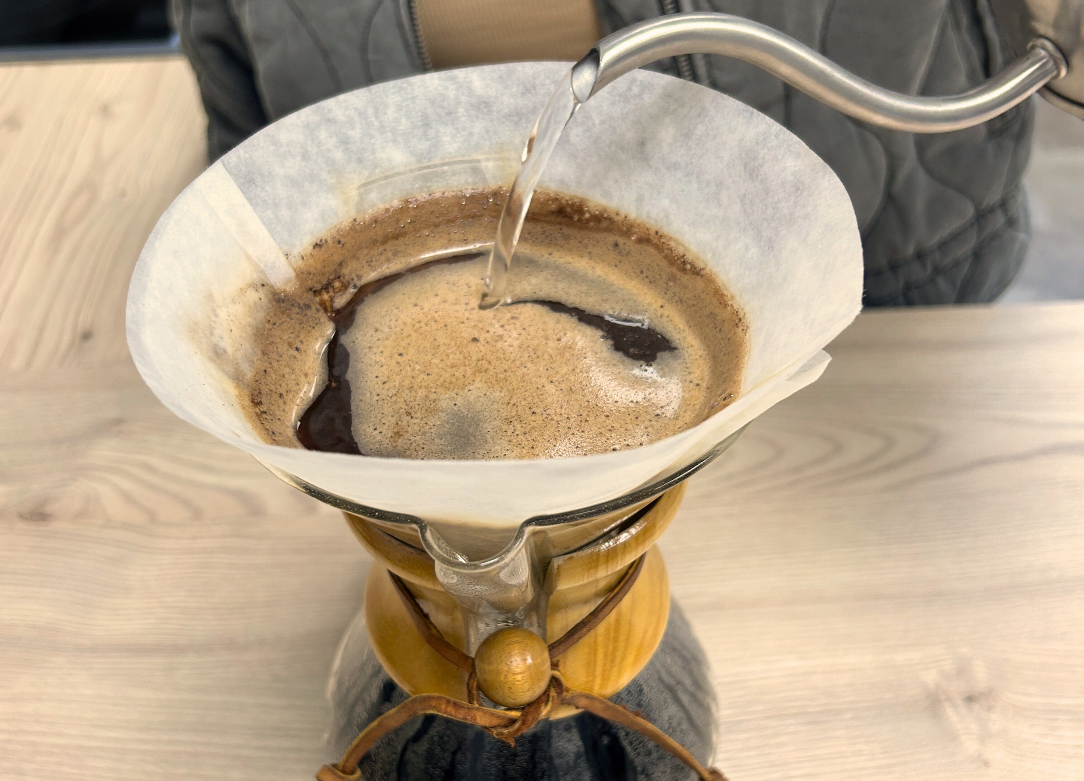 Heißes Wasser wird langsam über das Kaffeepulver im Filter einer Chemex-Karaffe gegossen, um den Brühvorgang fortzusetzen