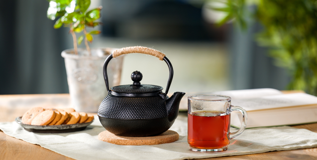 Auf einem Tisch stehen eine Teekanne und eine Glastasse mit frisch aufgebrühtem Darjeeling Tee