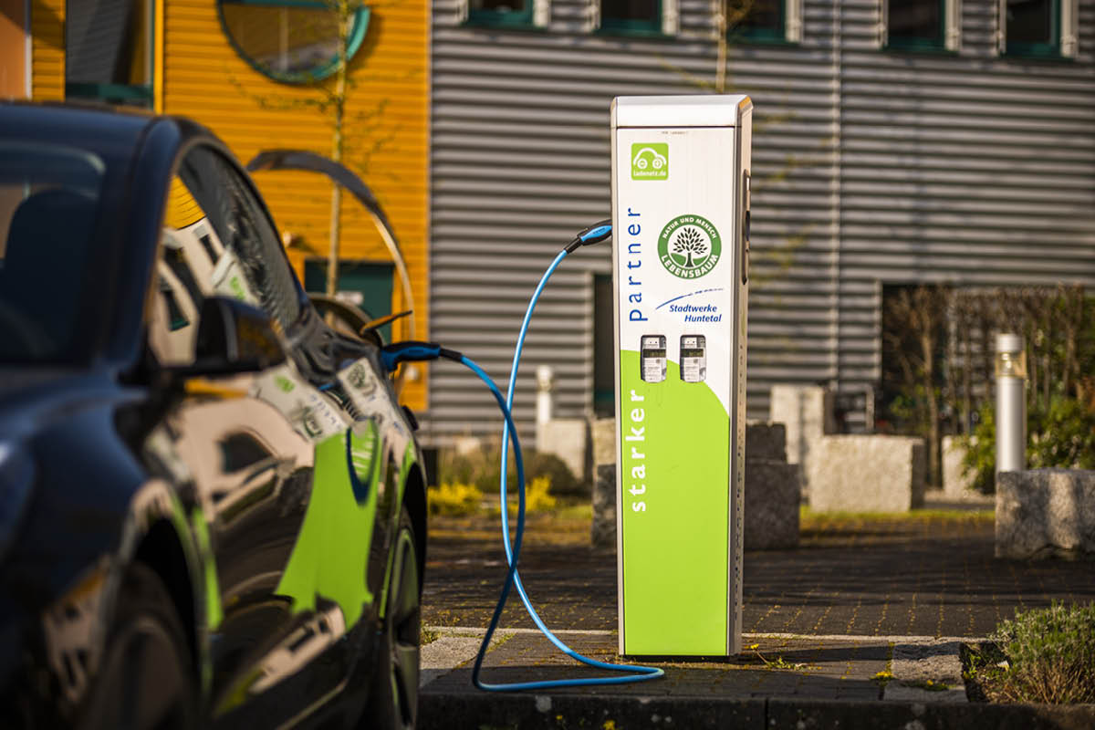 Schwarzes Auto an einer E-Ladesäule angeschlossen