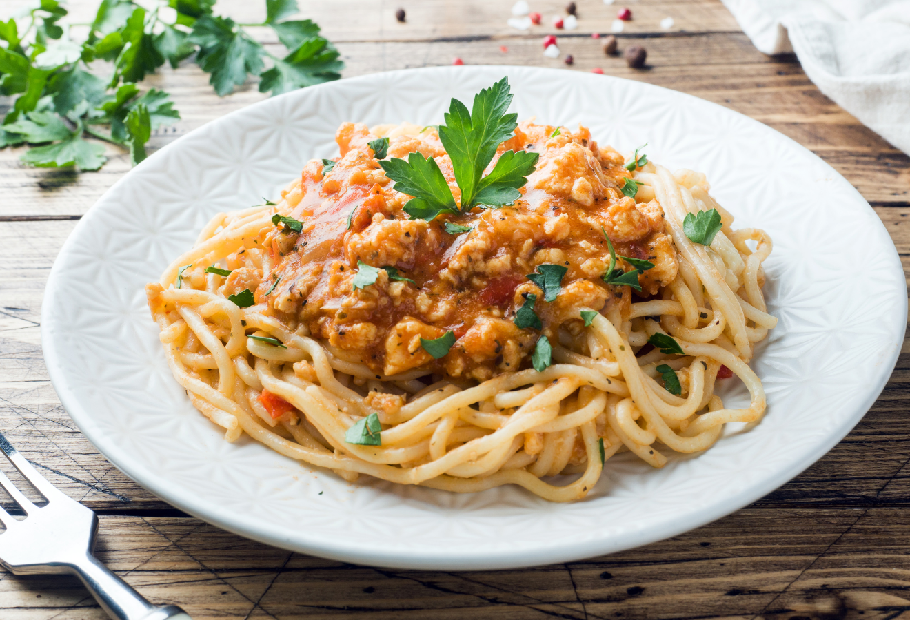  Spaghetti Bolognese vegan in einer weißen Schale mit Kräutern garniert