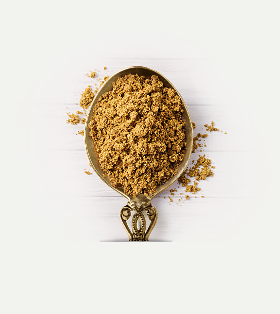 Garam Masala Gewürzmischung in goldenem Pulver auf antiker Messlöffel mit verstreutem Gewürz auf weißem Hintergrund.