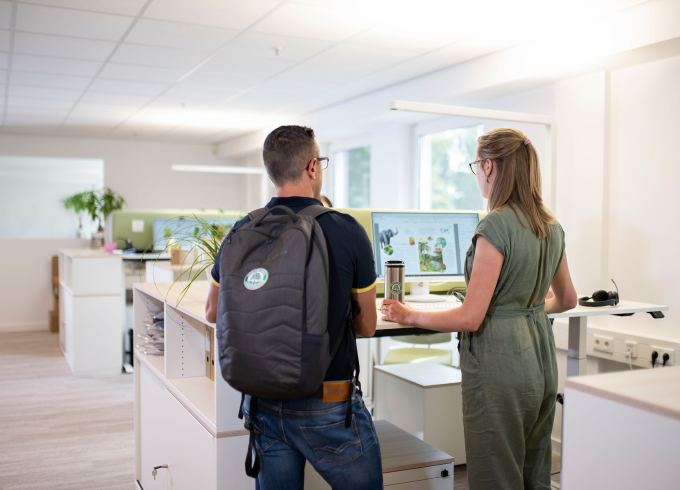 Zwei Personen in moderner Büroumgebung besprechen sich an einem Tresen, eine hält ein Produkt in der Hand.