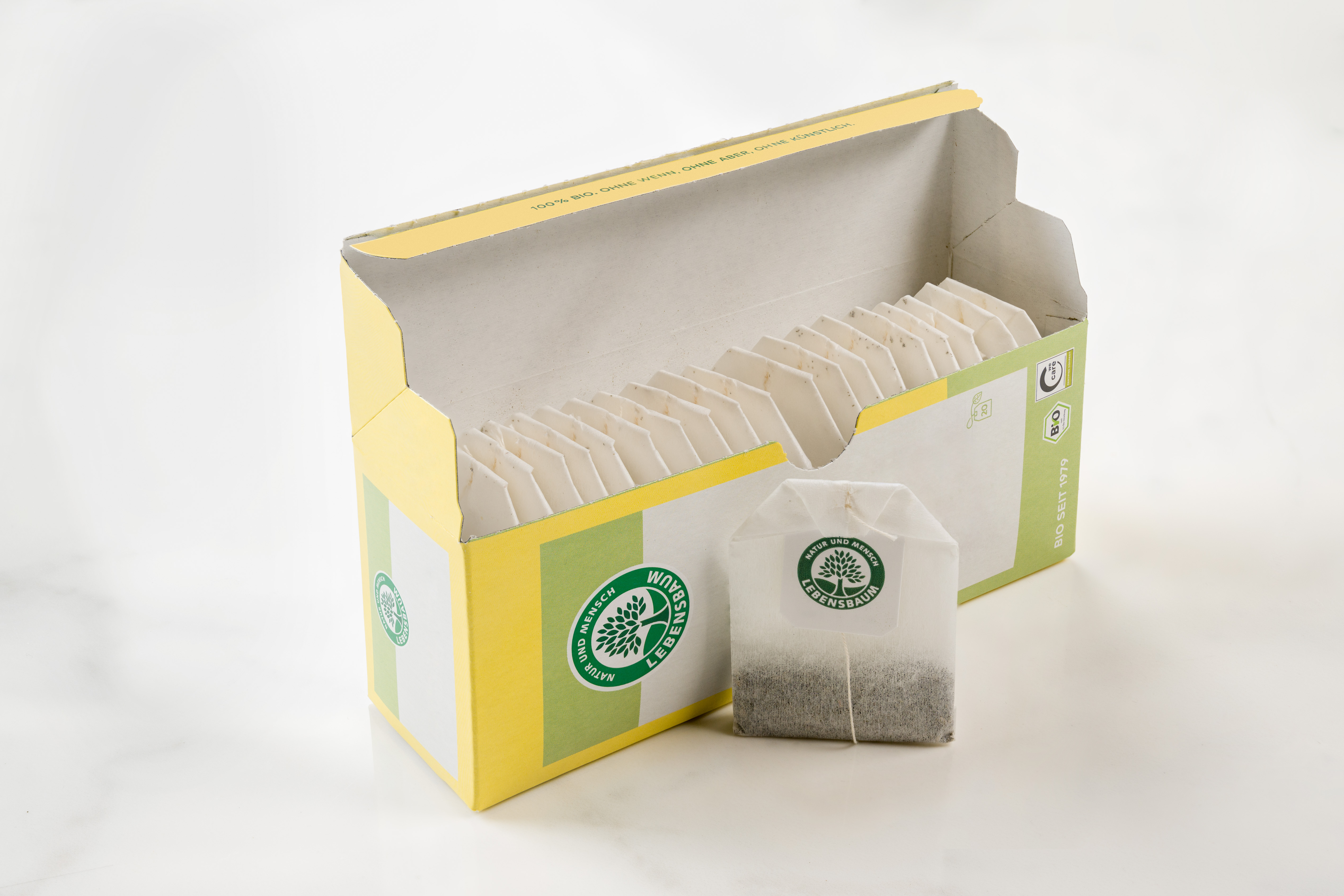 Teeboxen mit grünem Waldlogo auf gelb-grüner Verpackung, einzelner Teebeutel davor
