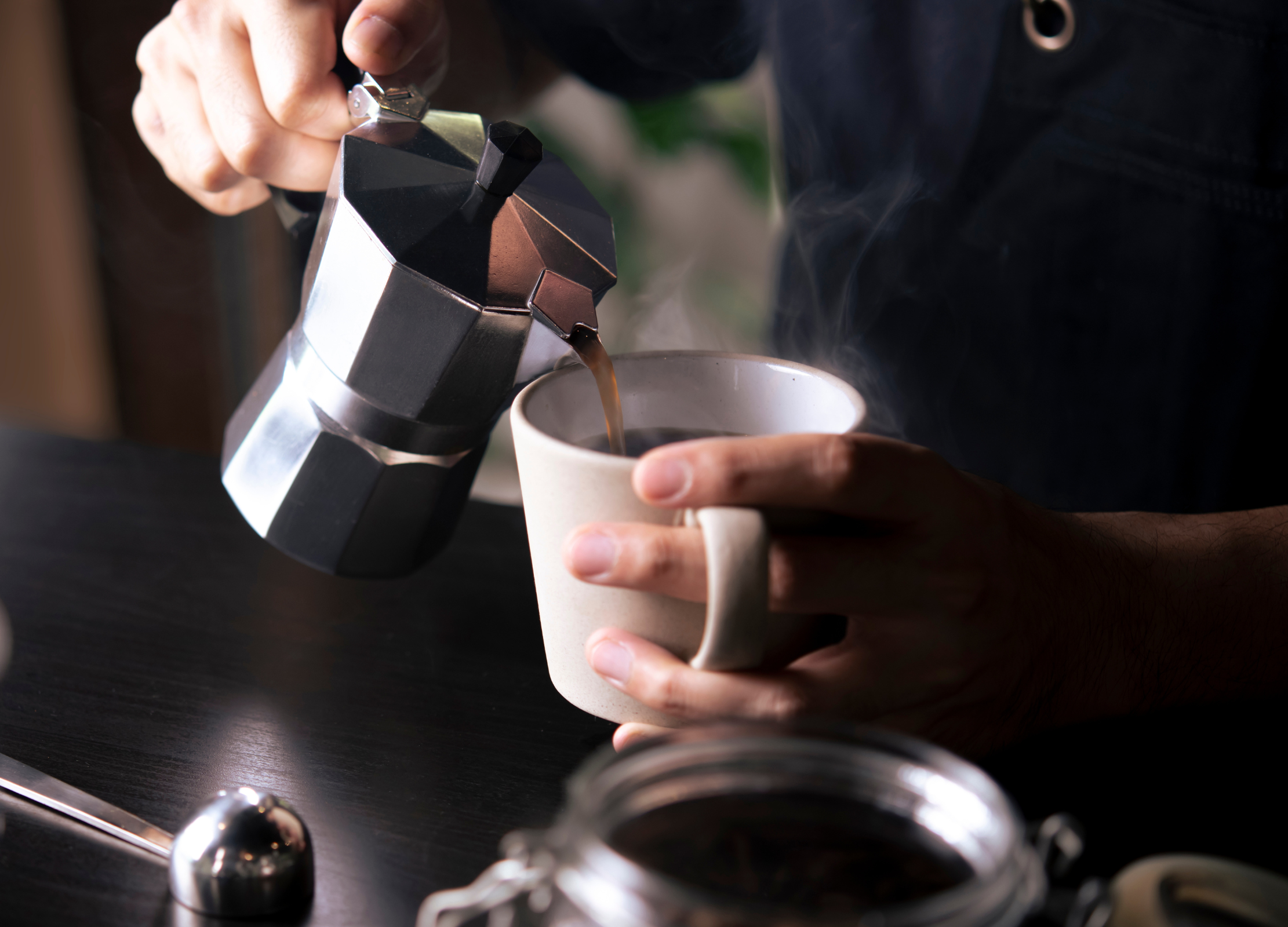 Frisch gebrühter Kaffee wird aus einer Espressokanne in eine Tasse gegossen