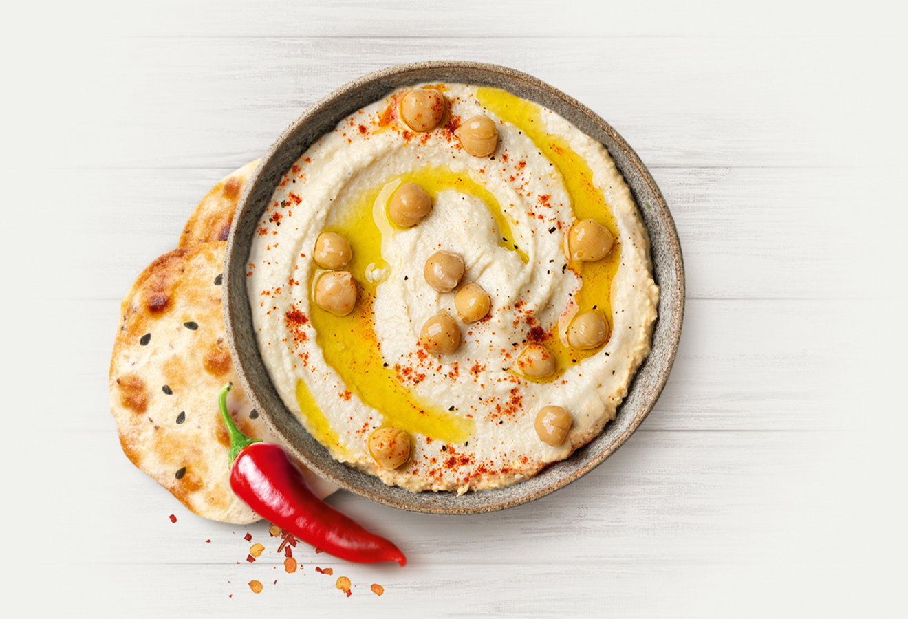Hummus-Dip in einer grauen Schale mit Kichererbsen und Öl garniert