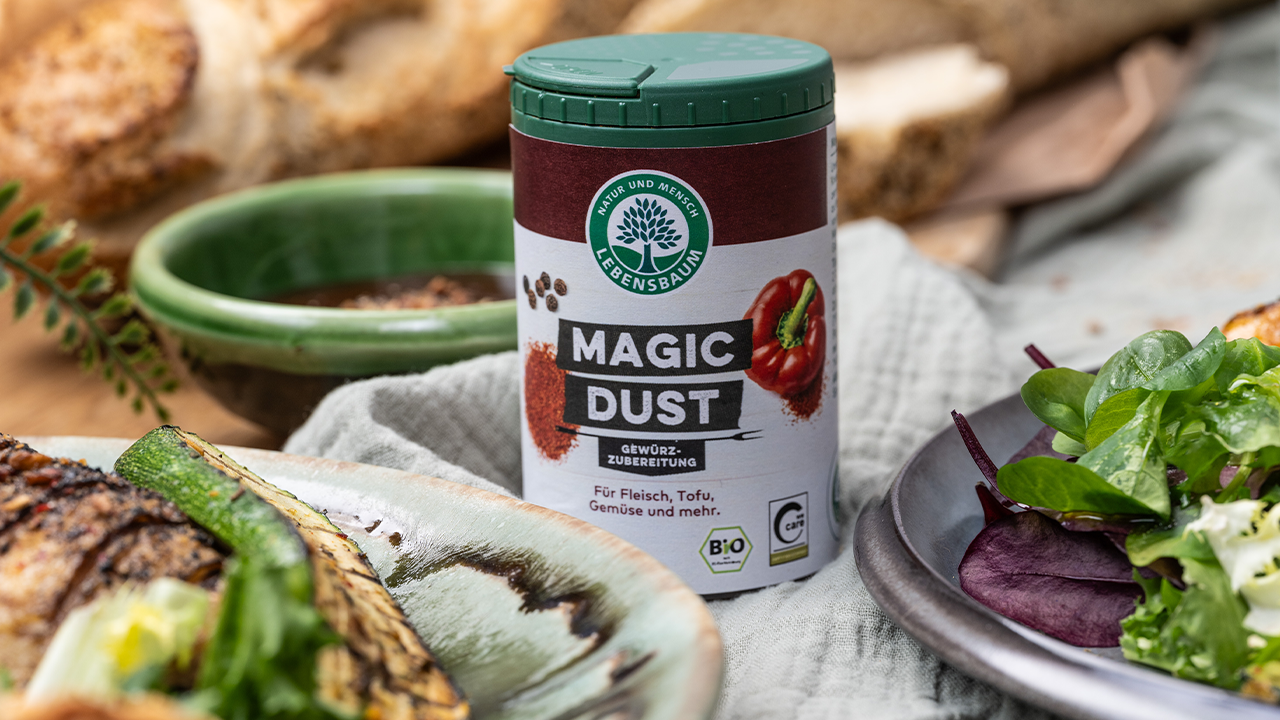 Lebensbaum Magic Dust Gewürzzubereitung in Dose mit grünem Deckel, umgeben von Grillgemüse und Kräutern auf rustikalem Untergrund.