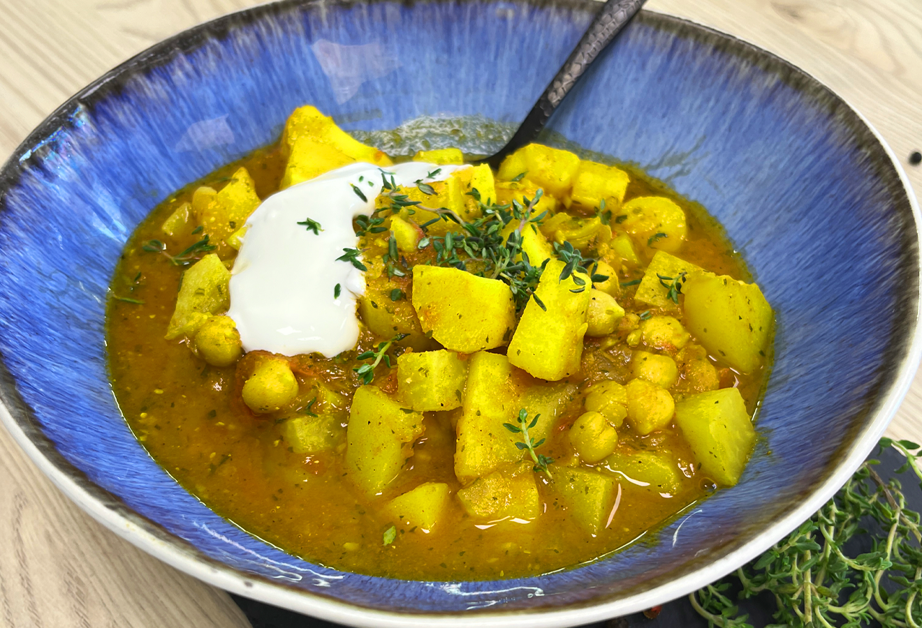 Pastinaken-Eintopf in blauer Schale mit Kartoffeln, Kichererbsen, Kräutern und Sauerrahm-Topping