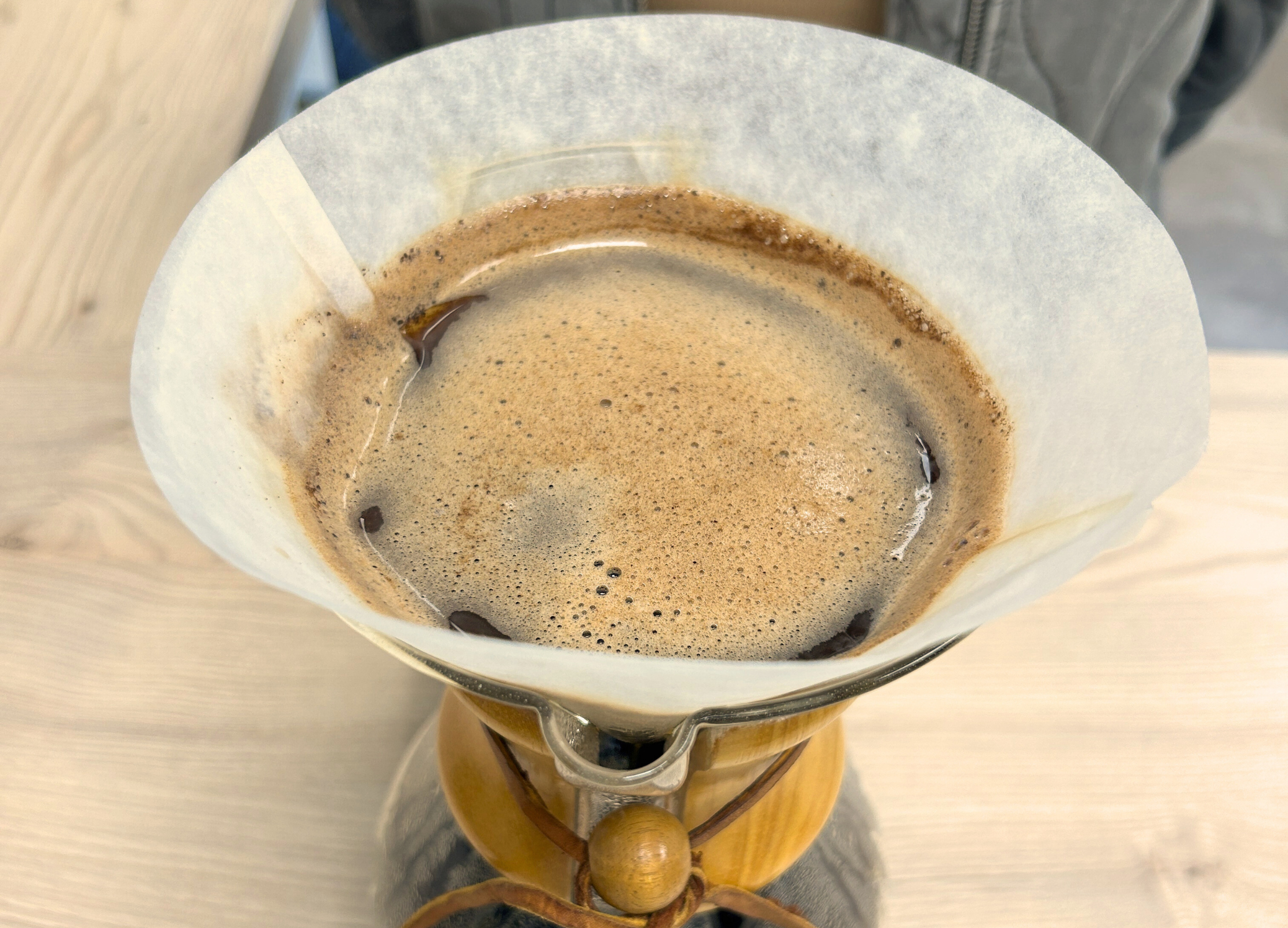 Frisch gebrühter Kaffee sammelt sich im Filter einer Chemex-Karaffe und bildet eine aromatische, schaumige Oberfläche