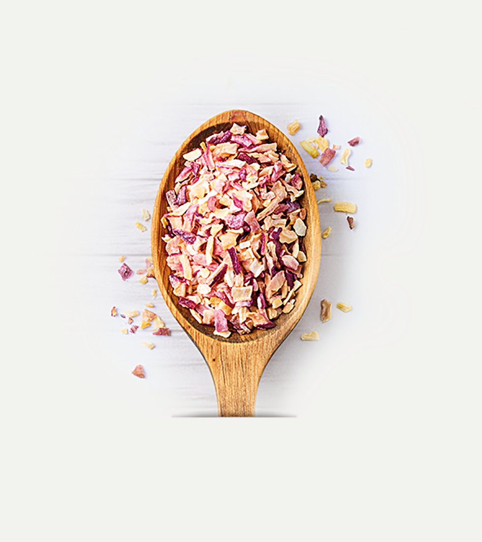 Getrocknete Zwiebelpflanzenteile in Rosa-, Rot- und Creme-Tönen auf Holzlöffel, einige Stücke verstreut daneben.