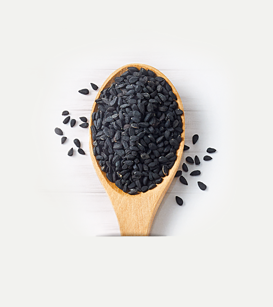 Schwarzkümmel-Körner in Holzlöffel, schwarze längliche Samen teilweise verstreut auf weißem Untergrund