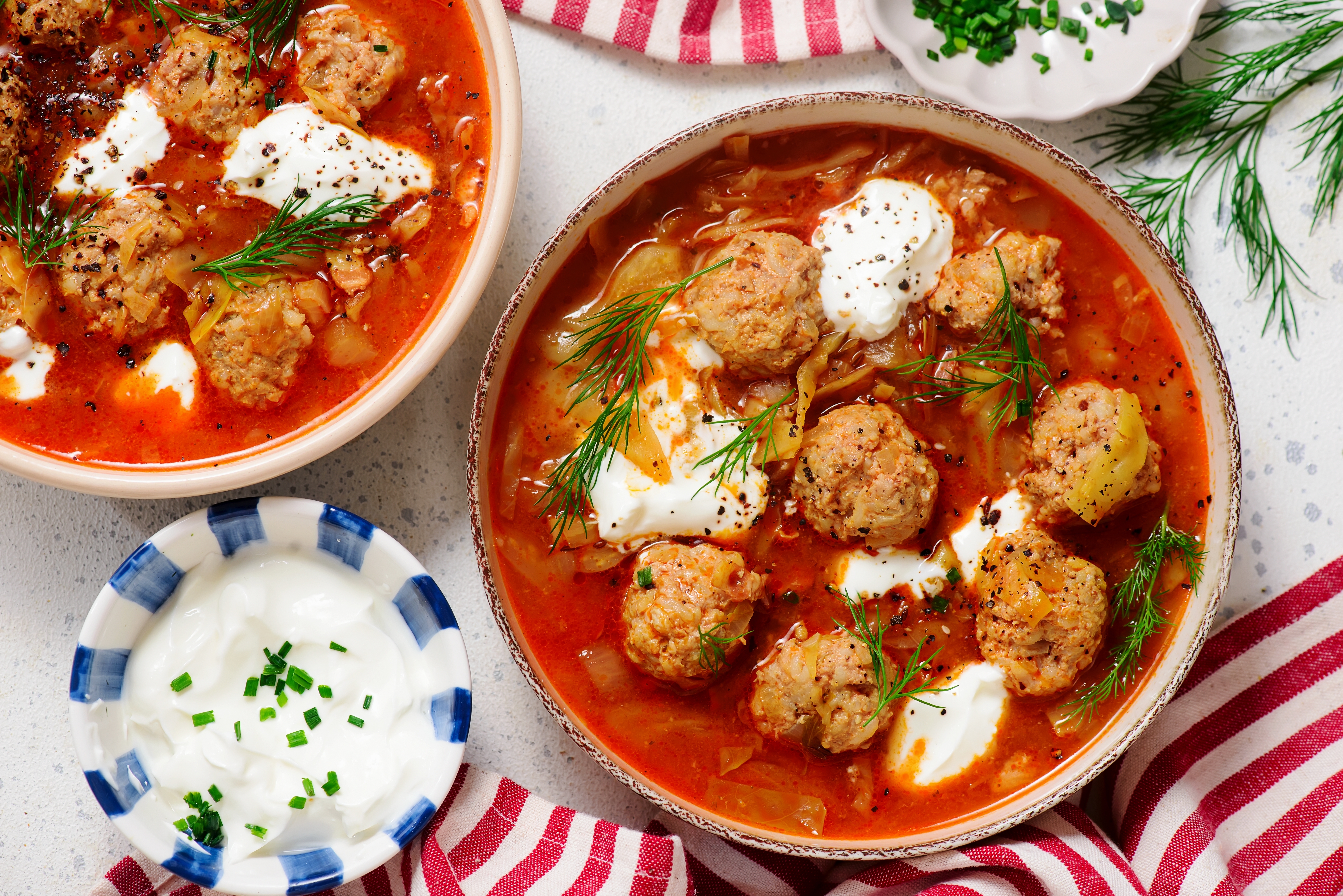 Ungarische Krautsuppe mit Fleischklößen: rote Brühe mit Kartoffeln, Sauerrahm und frischem Dill garniert